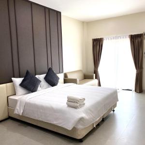 um quarto com uma grande cama branca e uma cadeira em The Shade Residence em Pattaya Central