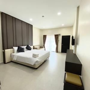 um quarto com uma grande cama branca e uma televisão em The Shade Residence em Pattaya Central