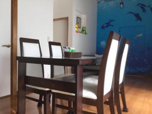 une table à manger avec quatre chaises et un mur bleu dans l'établissement 民泊大森, à Iyo