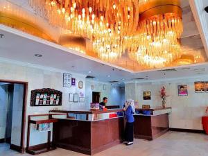 a woman standing at a bar in a restaurant at Hotel Grand Crystal in Alor Setar