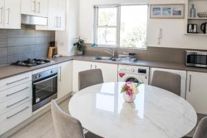 a kitchen with a table with a vase of flowers on it at Lotus Stay Manly - Apartment 29G in Sydney