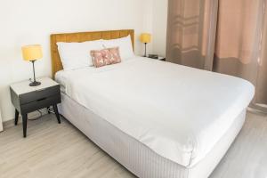 1 dormitorio con 1 cama blanca grande y 2 lámparas en Lotus Stay Manly - Apartment 29G, en Sídney