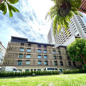 um edifício com uma palmeira em frente em The Shade Residence em Pattaya Central
