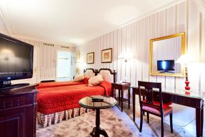 - un salon avec un lit rouge et une télévision dans l'établissement Golden Tulip Washington Opera, à Paris