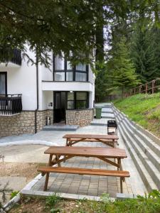 two wooden picnic tables in front of a building at Montana Residence in Poiana Brasov