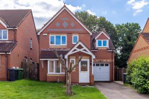 a red brick house with a white garage at Chandlers House in Peterborough