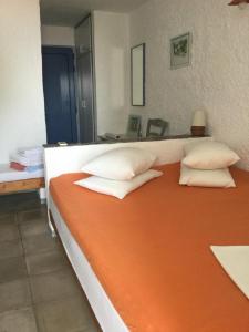 an orange and white bed with four pillows on it at Rosys Little Village in Skala