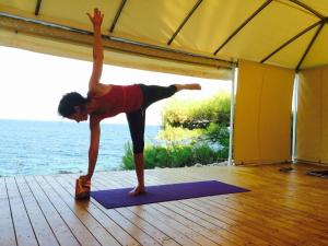 a woman doing a handstand on a yoga mat at Rosys Little Village in Skala