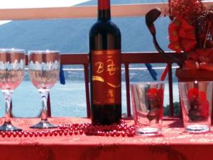 butelka wina na stole z kieliszkami w obiekcie Apartmani M Igalo Crna Gora w mieście Igalo