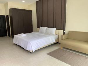 um quarto com uma cama branca e um sofá em The Shade Residence em Pattaya Central