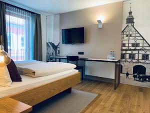 a hotel room with a bed and a tv on the wall at Stadthotel Kachelofen in Krumbach