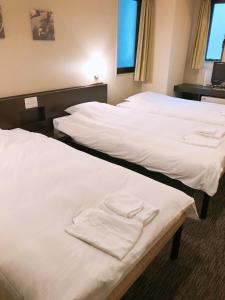 two beds in a hotel room with white sheets at Business Hotel Sunpu in Shizuoka
