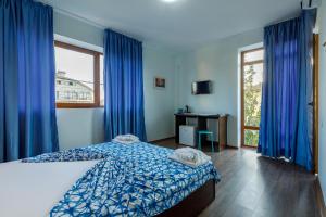 a bedroom with a bed and a window with blue curtains at Casa Lotca in Costinesti