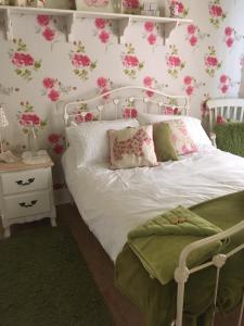 um quarto com uma cama branca com flores cor-de-rosa na parede em Ballyginniff Farm House em Crumlin