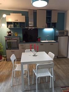 uma cozinha com uma mesa branca e cadeiras com velas vermelhas em Villa Raphaël em Cransac