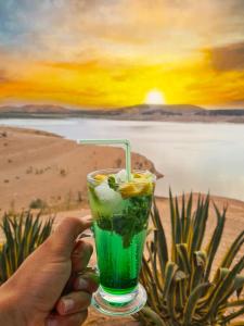 a person holding a green drink in front of a painting at Rive Du Lac in Lalla Takerkoust