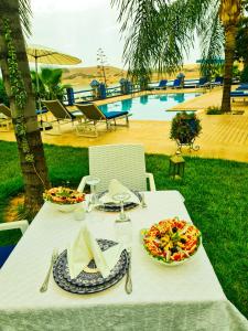 a white table with plates of food and a pool at Rive Du Lac in Lalla Takerkoust