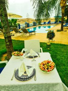 una mesa blanca con platos de comida y una piscina en Rive Du Lac, en Lalla Takerkoust