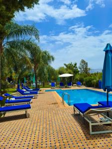 a row of blue lounge chairs next to a swimming pool at Rive Du Lac in Lalla Takerkoust