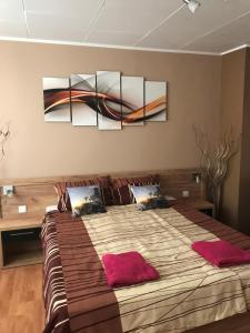 een slaapkamer met een groot bed met drie schilderijen aan de muur bij V&V Apartmani in Ćuprija