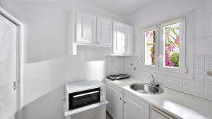 a white kitchen with a sink and a window at Marietta's in Mikonos