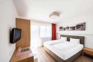 a bedroom with a white bed and a tv at Hotel Neuwirt in Finkenberg