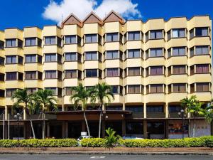 a large yellow building with palm trees in front of it at Hotel Grand Crystal in Alor Setar