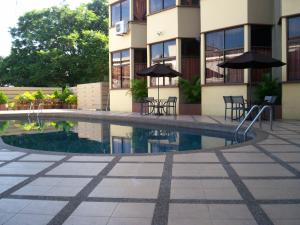 a swimming pool with chairs and umbrellas in front of a building at Hotel Grand Crystal in Alor Setar