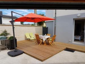 a patio with a table and a red umbrella at Appart 2-3 personnes proche plage de la Fresnaye in Saint-Cast-le-Guildo
