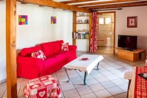 een woonkamer met een rode bank en een tafel bij Chez René in Ammerschwihr