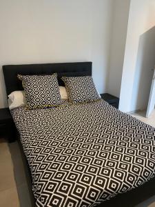 a bed with a black and white comforter and two pillows at le pavillon pierre naturelle in Jaujac