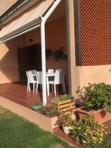 un patio con sillas blancas, mesas y plantas en La casa sotto la torre, en Chia