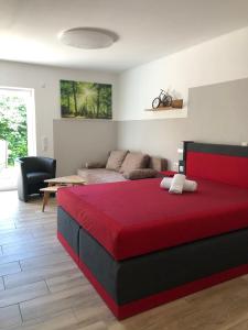 una camera con letto rosso e divano di Pension Zum Stein a Hohenkirchen