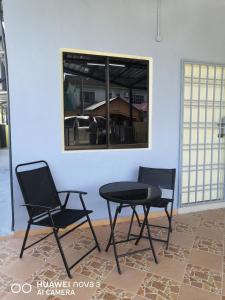 2 sillas y una mesa en una habitación con ventana en Abah 2 Room Homestay, en Pasir Gudang