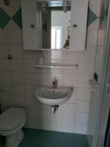 a bathroom with a sink and a toilet and a mirror at Il Glicine - Casa vacanza in Procida