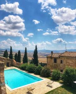 a swimming pool in front of a house with a view at Relais Il Chiostro Di Pienza in Pienza