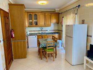 uma cozinha com uma mesa e um frigorífico branco em Apartamento Praia de Altura-Terraço BBQ-Wfi-AC em Altura