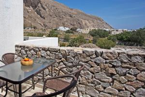 a table and chairs on a patio with a stone wall at Birds Villa Apartments - Including Car Rental in Perissa