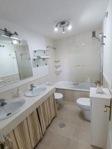 a bathroom with two sinks and a tub and a toilet at Mi Capricho in Sitio de Calahonda