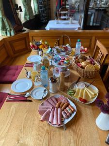 einem Holztisch mit Teller mit Lebensmitteln darauf in der Unterkunft Runa´s Hotel in Hallbergmoos