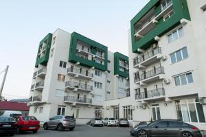 a tall building with cars parked in a parking lot at Urban Apartment in Oradea