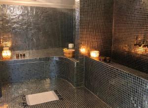 a black tiled bathroom with a tub and a toilet at Domaine de Tameslohte in Tameslouht