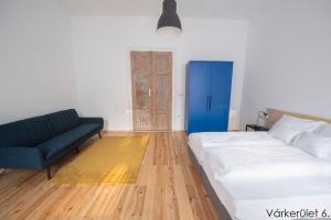 a bedroom with a bed and a blue couch at Várkerület 6 Apartman in Sárvár