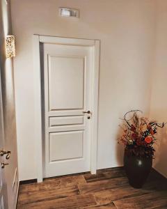 - une porte blanche dans une chambre avec un vase de fleurs dans l'établissement B&B Duca Orsini, à Gravina in Puglia