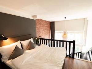 um quarto com uma cama com lençóis brancos e almofadas em PHNX Aparthotel Hamburg em Hamburgo
