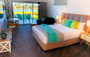 a bedroom with a large bed and a table and chairs at Ulverstone River Edge HolidayApartments in Ulverstone