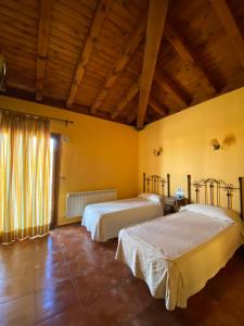 two beds in a room with yellow walls and wooden ceilings at Hotel Hostería de Monzón in Monzón de Campos