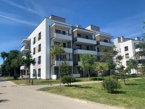 a white apartment building with trees in front of it at Apartament Emilia Ustronie Morskie in Ustronie Morskie