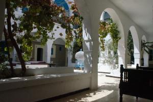 um pátio com arcos e uma árvore num edifício em Hôtel Djerba Erriadh em Houmt Souk