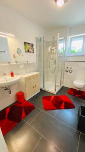 un bagno con lavandino, doccia e tappetini rossi di Moderne Wohnung im Rhein-Main-Gebiet a Idstein